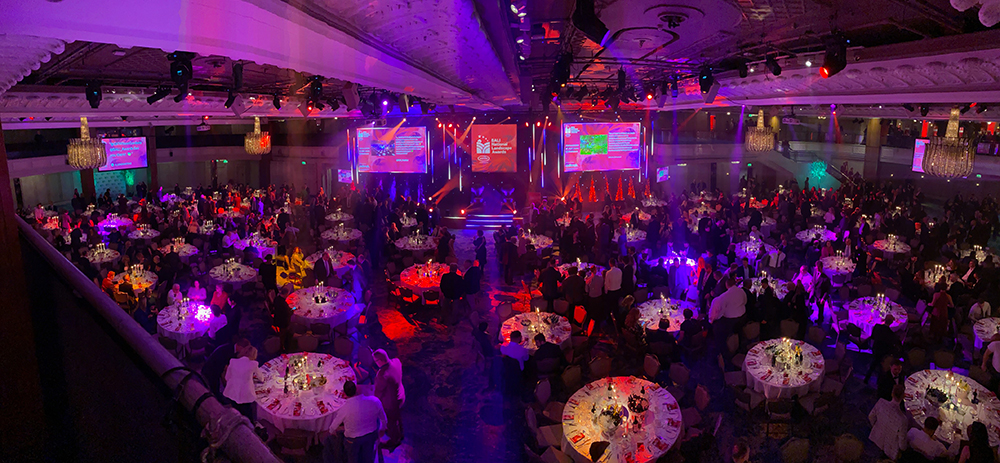 An image of an awards ceremony taking place in a conference hall with many guests seated around tables