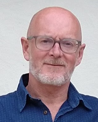 An image of a gentleman in glasses and shirt and tie, against a blank background